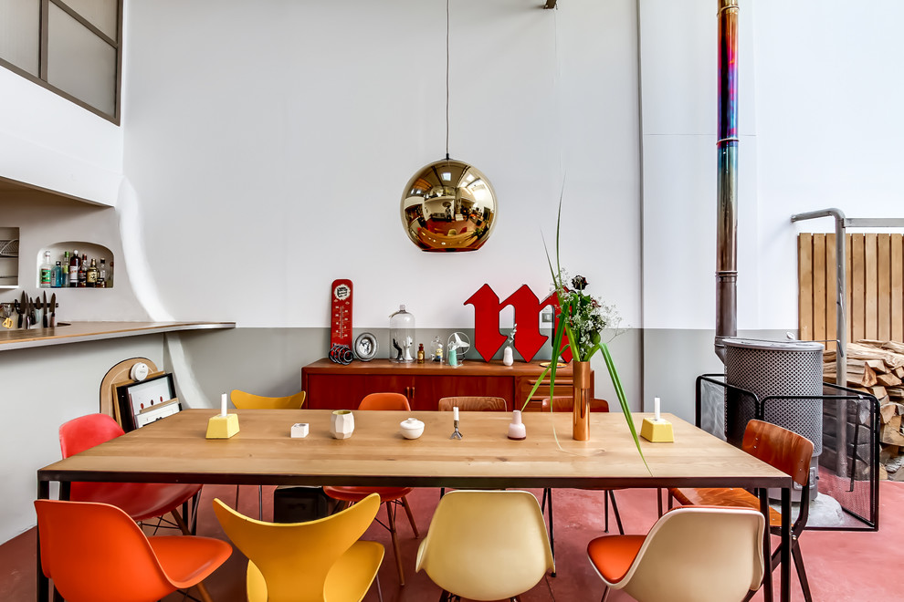 Design ideas for a mid-sized eclectic open plan dining in Paris with multi-coloured walls, a metal fireplace surround and red floor.