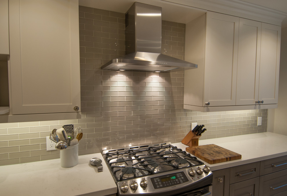 Enclosed kitchen - mid-sized transitional galley ceramic tile enclosed kitchen idea in Toronto with shaker cabinets, white cabinets, quartzite countertops, gray backsplash, glass tile backsplash, stainless steel appliances and no island