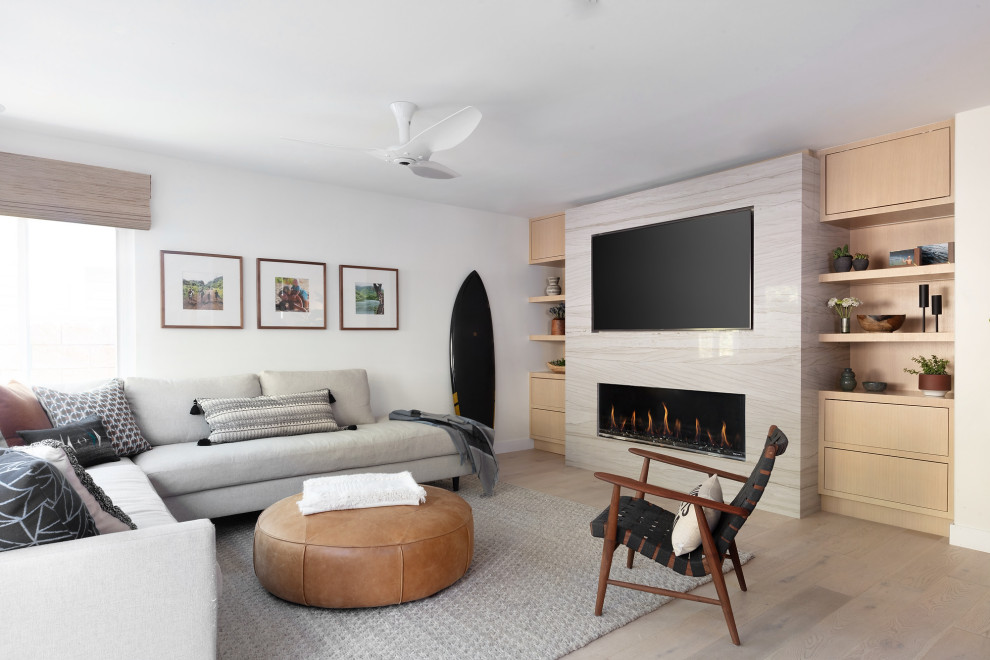 Источник вдохновения для домашнего уюта: гостиная комната в современном стиле с белыми стенами, паркетным полом среднего тона, горизонтальным камином, фасадом камина из камня, телевизором на стене и коричневым полом