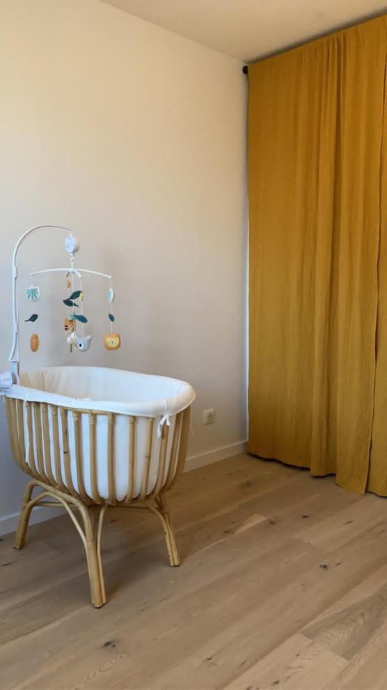 This is an example of a mid-sized scandinavian gender-neutral nursery in Other with white walls, light hardwood floors and beige floor.