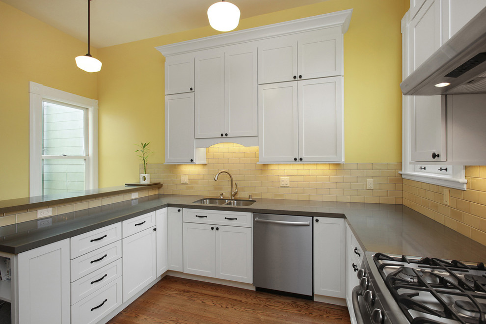 This is an example of a traditional u-shaped kitchen pantry in San Francisco with an undermount sink, shaker cabinets, white cabinets, quartz benchtops, yellow splashback, glass tile splashback, stainless steel appliances and medium hardwood floors.