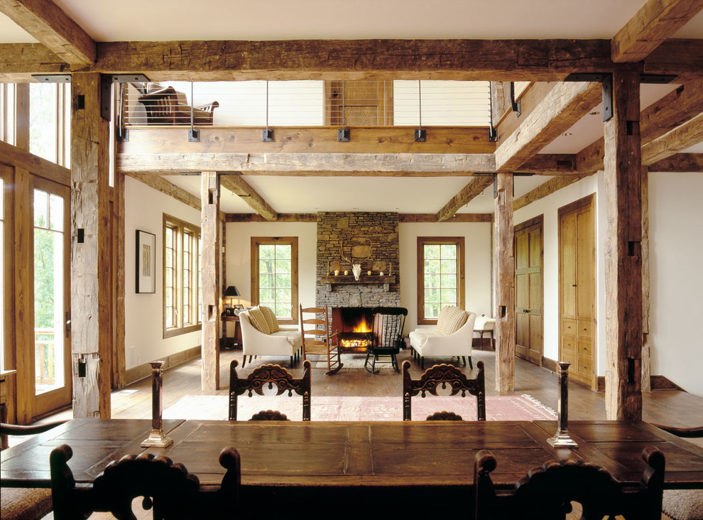 This is an example of a large country formal living room in New York with white walls, dark hardwood floors, a standard fireplace, a stone fireplace surround and no tv.