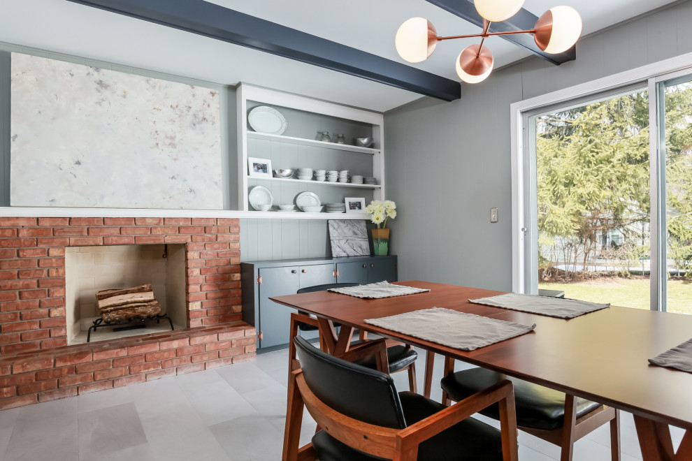Design ideas for a mid-sized midcentury kitchen/dining combo in Grand Rapids with grey walls, vinyl floors, a standard fireplace, a brick fireplace surround, white floor, exposed beam and panelled walls.