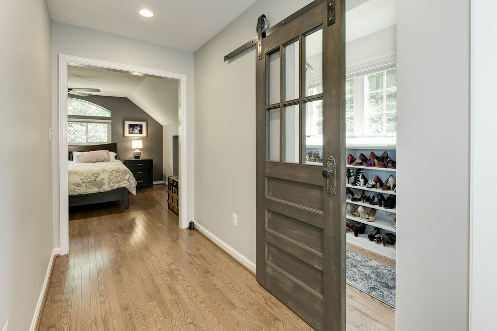 Design ideas for a mid-sized transitional gender-neutral walk-in wardrobe in DC Metro with open cabinets, white cabinets, light hardwood floors and brown floor.