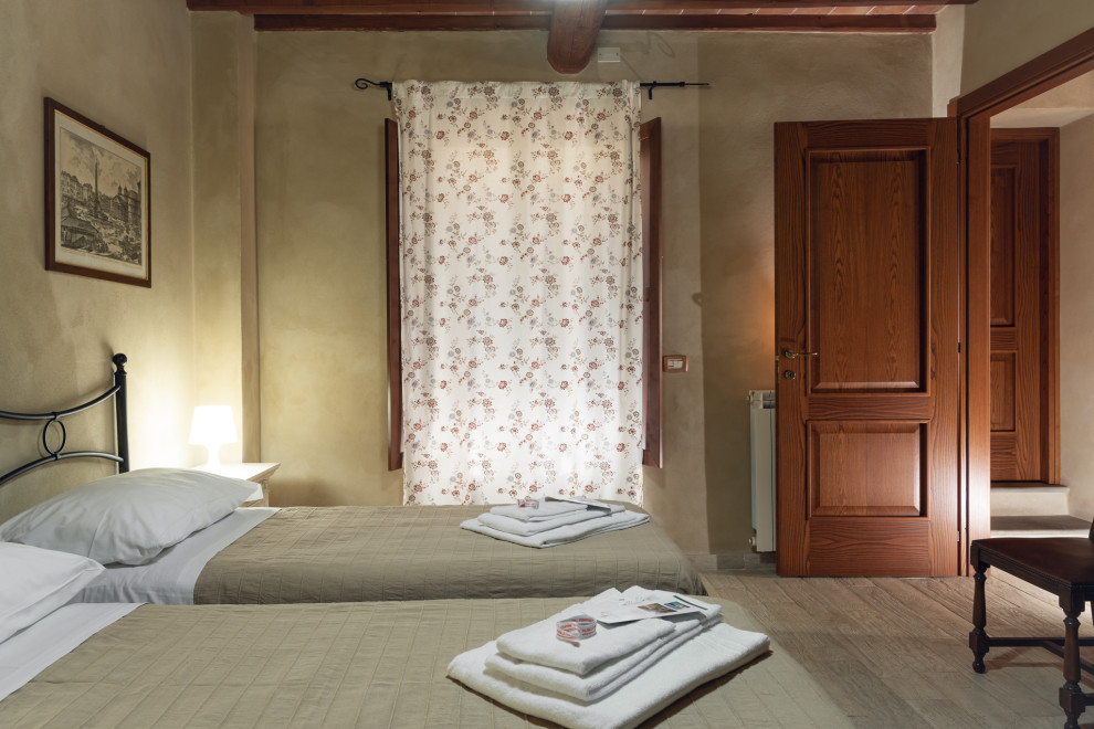Diseño de habitación de invitados rural pequeña con paredes beige, suelo de baldosas de porcelana, suelo gris y vigas vistas