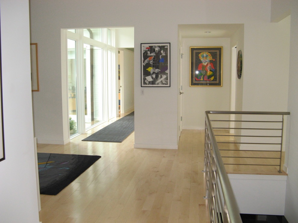 This is an example of a mid-sized modern hallway in Cincinnati with white walls and light hardwood floors.