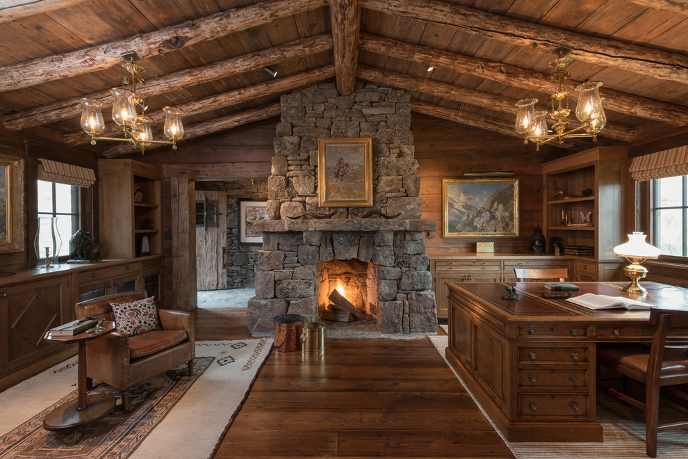 This is an example of a country study room in Other with medium hardwood floors, a standard fireplace, a stone fireplace surround and a freestanding desk.