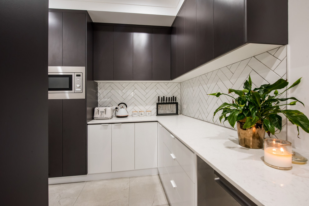 Large contemporary galley kitchen pantry in Other with a drop-in sink, flat-panel cabinets, white cabinets, granite benchtops, white splashback, subway tile splashback, black appliances, ceramic floors, with island, grey floor and white benchtop.