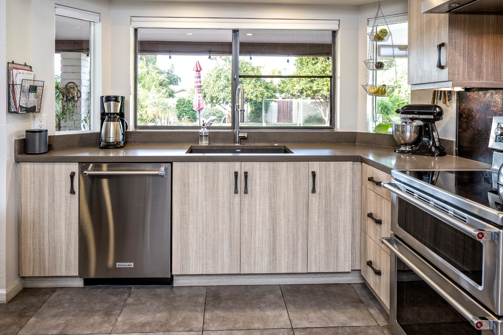 This is an example of a large industrial l-shaped eat-in kitchen in Phoenix with a drop-in sink, flat-panel cabinets, light wood cabinets, concrete benchtops, brown splashback, metal splashback, stainless steel appliances, ceramic floors, with island and grey floor.