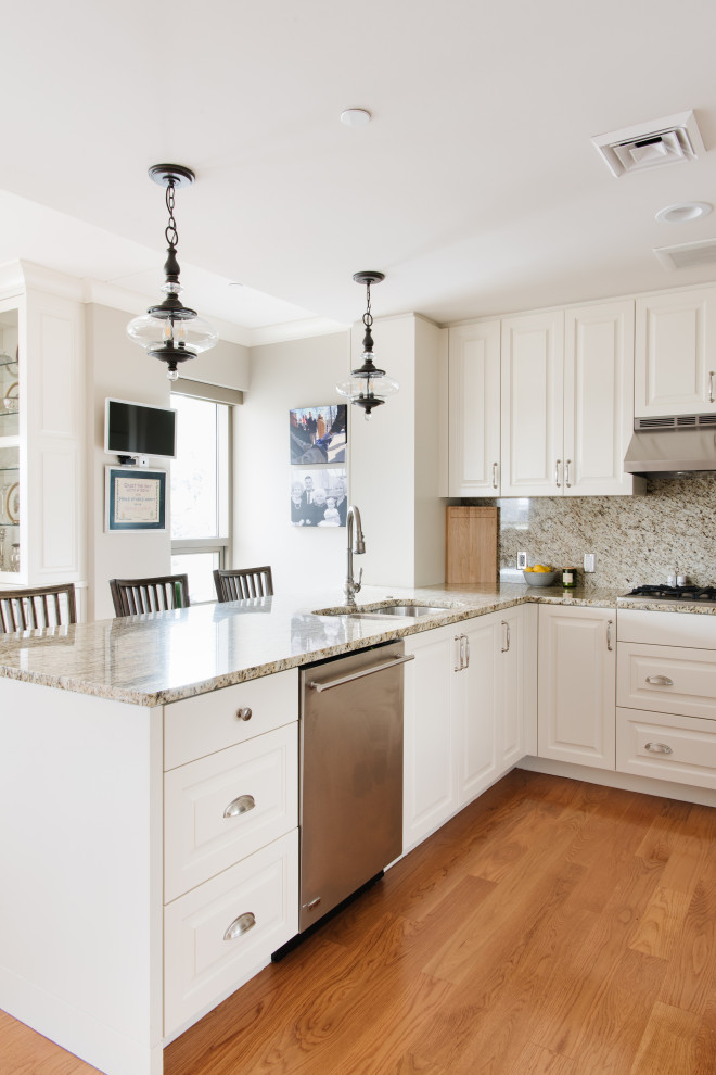 This is an example of a mid-sized arts and crafts kitchen in Salt Lake City with white cabinets, granite benchtops, beige splashback, granite splashback, stainless steel appliances, medium hardwood floors and beige benchtop.