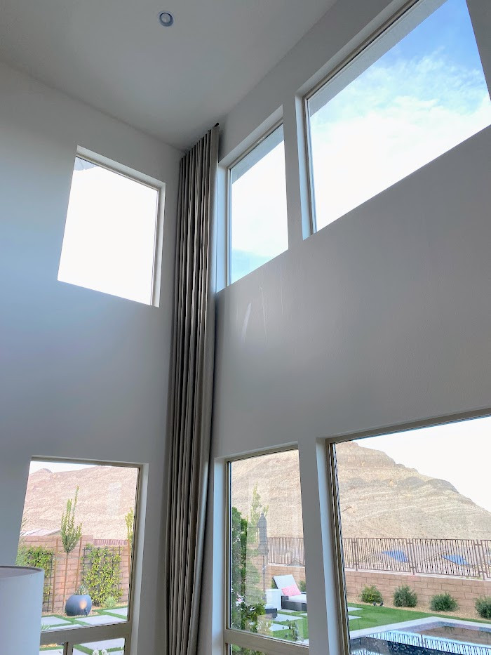 Geräumiges, Offenes Modernes Wohnzimmer mit weißer Wandfarbe, Vinylboden, grauem Boden, Kamin und Kaminumrandung aus Stein in Las Vegas