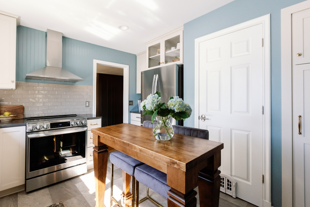 Inspiration for a small timeless u-shaped vinyl floor and gray floor enclosed kitchen remodel with a farmhouse sink, shaker cabinets, white cabinets, quartz countertops, beige backsplash, subway tile backsplash, stainless steel appliances, an island and black countertops