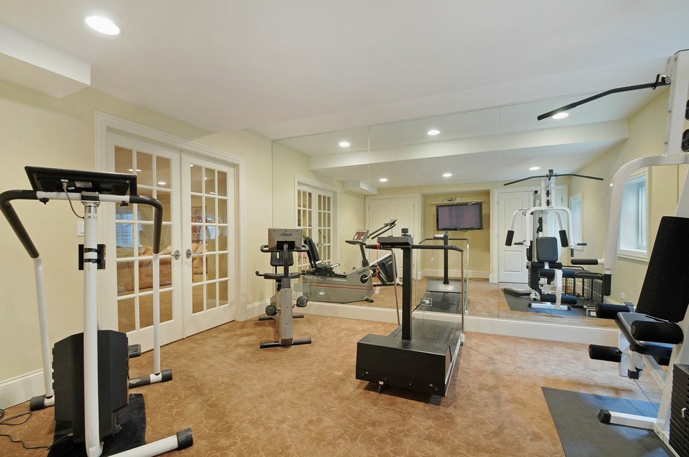 This is an example of a mid-sized traditional home weight room in Chicago with beige walls, concrete floors and brown floor.