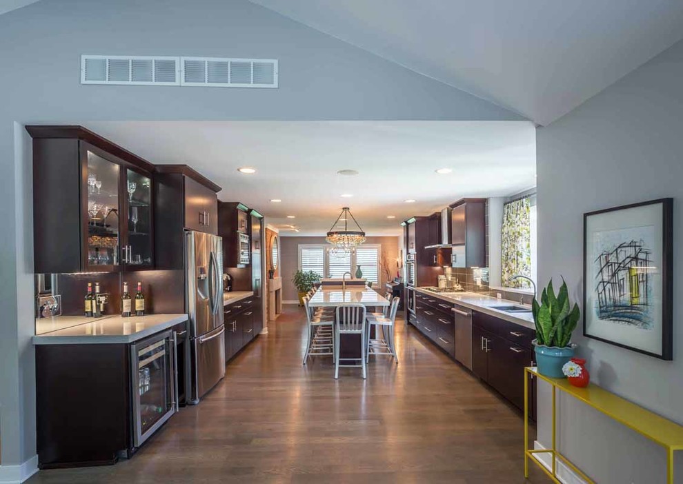 Design ideas for a mid-sized contemporary galley eat-in kitchen in Chicago with a drop-in sink, shaker cabinets, dark wood cabinets, limestone benchtops, grey splashback, ceramic splashback, stainless steel appliances, light hardwood floors, with island, brown floor, grey benchtop and vaulted.