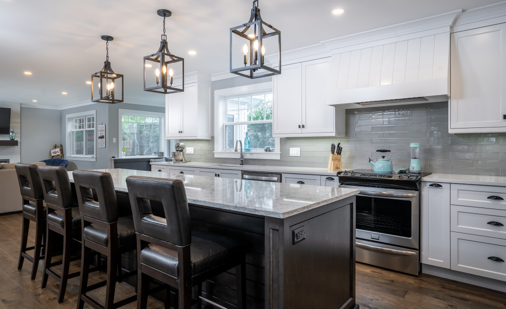 Kitchen - large transitional l-shaped medium tone wood floor and brown floor kitchen idea with an undermount sink, white cabinets, quartz countertops, white backsplash, glass tile backsplash, stainless steel appliances, an island and white countertops