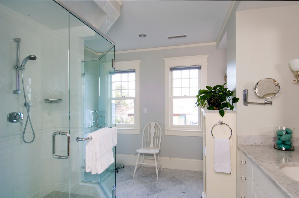 Inspiration for a mid-sized traditional master bathroom in Portland Maine with recessed-panel cabinets, white cabinets, an alcove shower, white tile, ceramic tile, grey walls, ceramic floors, an integrated sink, marble benchtops, grey floor and a hinged shower door.