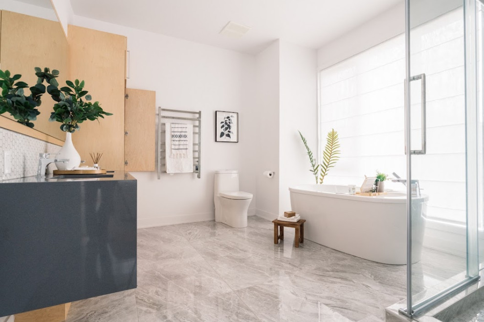 Photo of an expansive scandinavian master bathroom in Montreal with flat-panel cabinets, light wood cabinets, a freestanding tub, an alcove shower, a one-piece toilet, white walls, ceramic floors, an integrated sink, engineered quartz benchtops, grey floor, a sliding shower screen, grey benchtops, a double vanity, a built-in vanity and recessed.