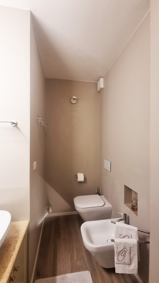 Idée de décoration pour un WC suspendu design de taille moyenne avec un placard avec porte à panneau encastré, des portes de placard beiges, un mur beige, parquet clair, une vasque, un plan de toilette en marbre, un sol beige, un plan de toilette beige et meuble-lavabo encastré.