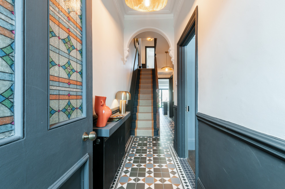 Ispirazione per un corridoio eclettico di medie dimensioni con pareti blu, pavimento in gres porcellanato, una porta singola, una porta arancione e pavimento multicolore