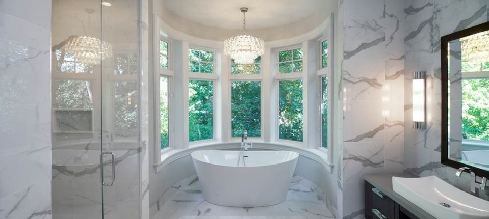 This is an example of a large contemporary master bathroom in Detroit with flat-panel cabinets, brown cabinets, a freestanding tub, a curbless shower, a one-piece toilet, white tile, marble, white walls, marble floors, a pedestal sink, concrete benchtops, white floor and a hinged shower door.