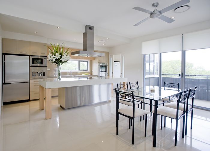 This is an example of a mid-sized contemporary galley open plan kitchen in Sunshine Coast with a drop-in sink, flat-panel cabinets, light wood cabinets, quartz benchtops, beige splashback, glass sheet splashback, stainless steel appliances, porcelain floors and with island.