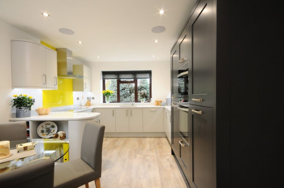 Inspiration for a mid-sized contemporary galley eat-in kitchen in Other with a drop-in sink, flat-panel cabinets, grey cabinets, soapstone benchtops, yellow splashback, glass sheet splashback, stainless steel appliances, light hardwood floors, no island, multi-coloured floor and multi-coloured benchtop.