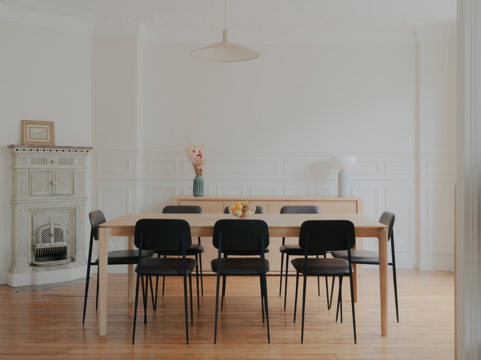 Inspiration pour une salle à manger minimaliste avec un mur blanc, parquet clair, une cheminée d'angle, un sol beige et boiseries.