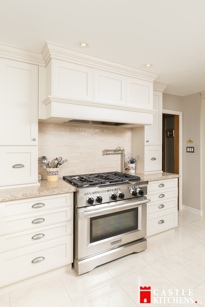 Enclosed kitchen - mid-sized transitional galley porcelain tile enclosed kitchen idea in Toronto with an undermount sink, shaker cabinets, beige cabinets, quartzite countertops, beige backsplash, stainless steel appliances and an island