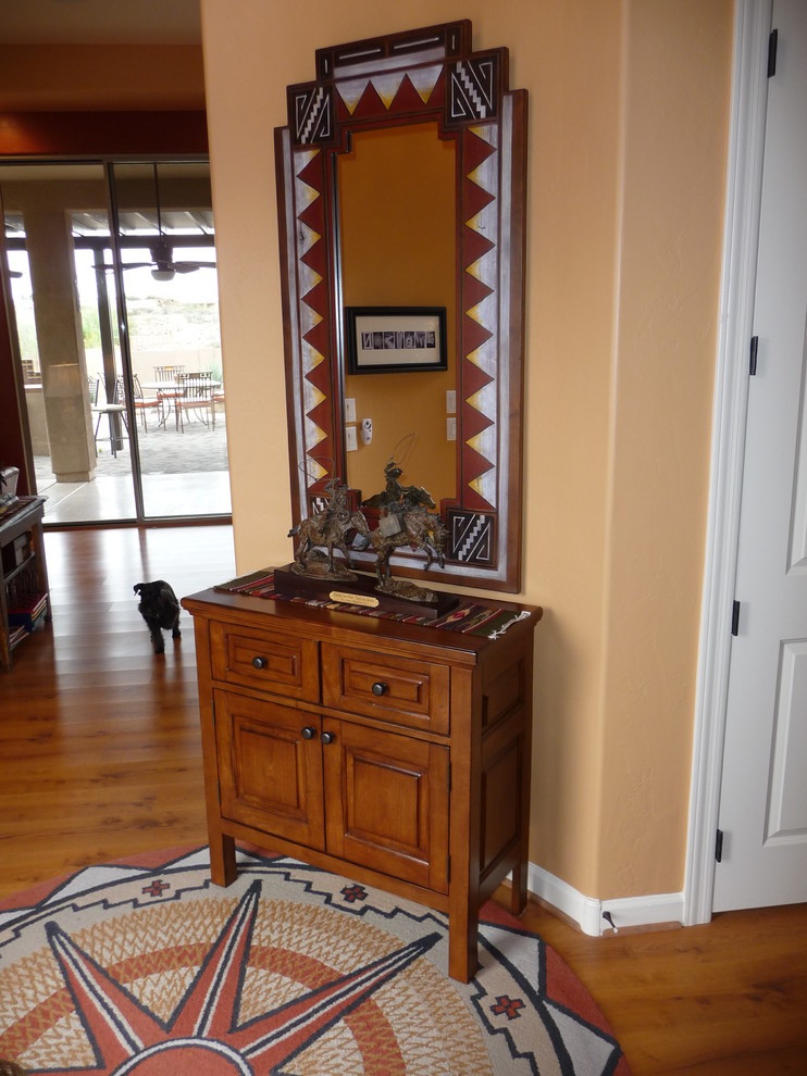 This is an example of a mid-sized foyer in Phoenix with orange walls, light hardwood floors and brown floor.