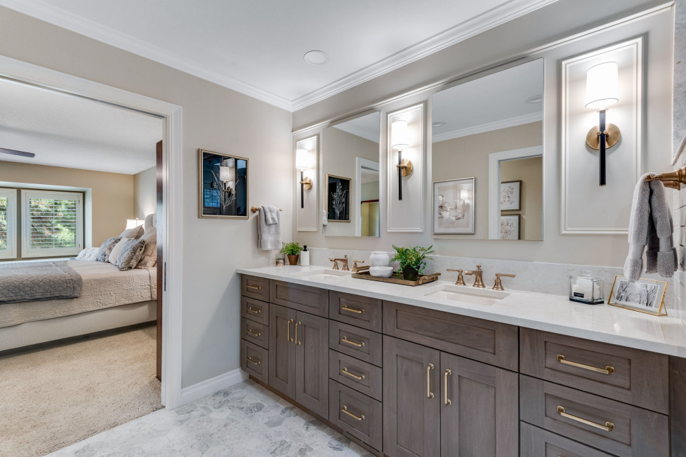 This is an example of a medium sized traditional ensuite bathroom in Denver with recessed-panel cabinets, brown cabinets, an alcove shower, a one-piece toilet, white tiles, metro tiles, beige walls, marble flooring, a submerged sink, engineered stone worktops, white floors, a hinged door, white worktops, a wall niche, double sinks, a built in vanity unit and panelled walls.