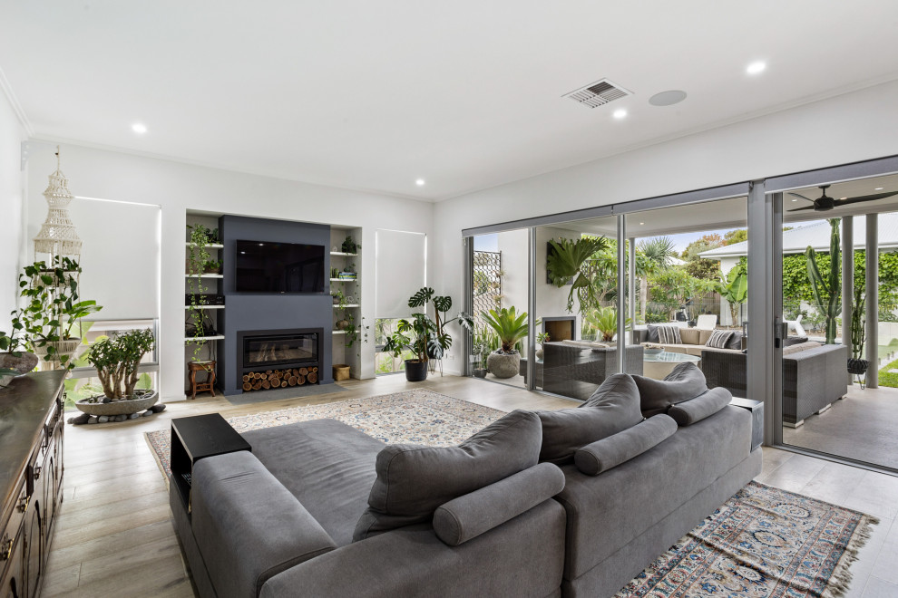 Photo of a contemporary open concept living room in Perth with white walls, medium hardwood floors, a ribbon fireplace, a wall-mounted tv and brown floor.