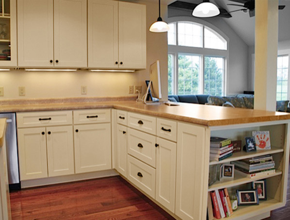 This is an example of a traditional l-shaped eat-in kitchen in Philadelphia with a farmhouse sink, raised-panel cabinets, black cabinets, stainless steel benchtops, white splashback, stone tile splashback and stainless steel appliances.