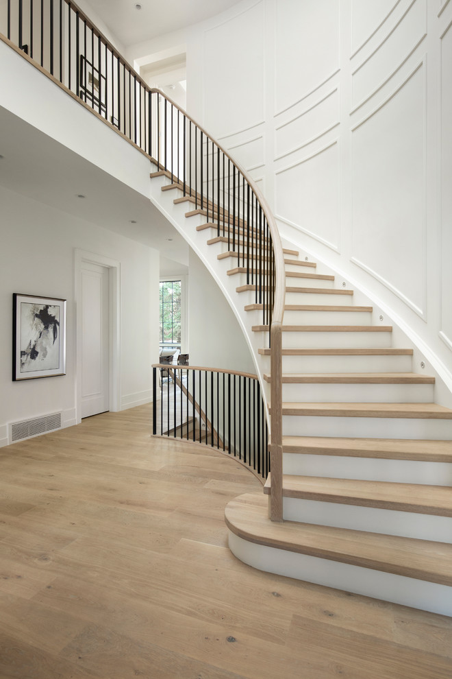 Transitional wood curved staircase in Calgary with painted wood risers and mixed railing.