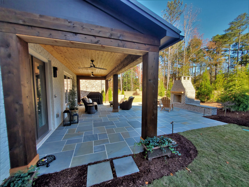 Idee per un patio o portico chic di medie dimensioni e dietro casa con un caminetto, pavimentazioni in pietra naturale e un tetto a sbalzo