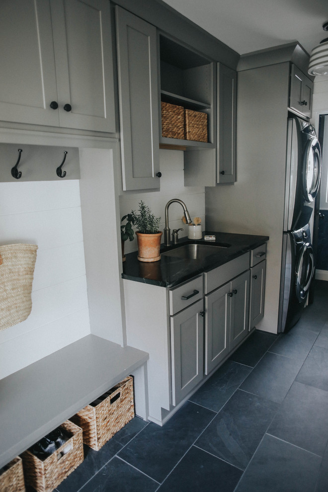 This is an example of a mid-sized transitional single-wall dedicated laundry room in Burlington with shaker cabinets, grey cabinets, soapstone benchtops, white walls, slate floors and black floor.