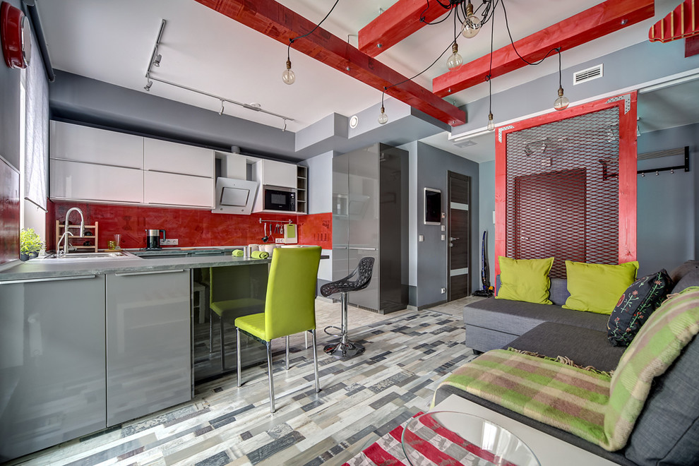 Foto på ett stort industriellt kök, med en dubbel diskho, släta luckor, grå skåp, laminatbänkskiva, rött stänkskydd, klinkergolv i keramik och en halv köksö