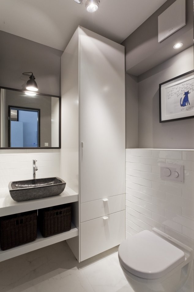 Inspiration for a mid-sized contemporary powder room in Berlin with a wall-mount toilet, white tile, grey walls, ceramic floors, a vessel sink, marble benchtops, white floor, open cabinets, brown cabinets and subway tile.