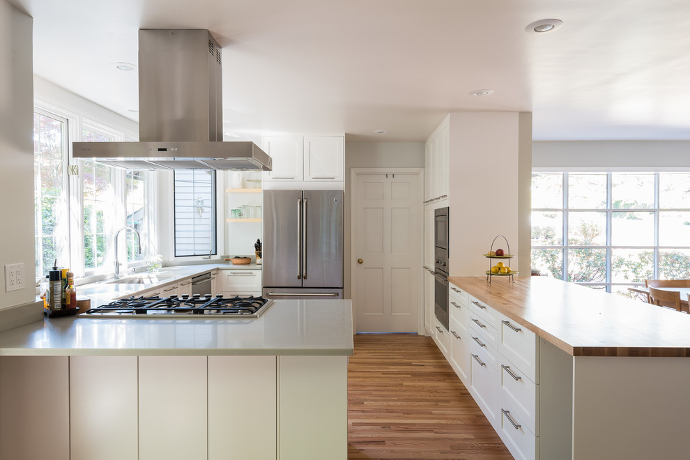 This is an example of a mid-sized contemporary separate kitchen in Seattle with an undermount sink, recessed-panel cabinets, white cabinets, wood benchtops, light hardwood floors and no island.
