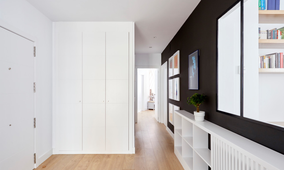 Mid-sized modern foyer in Madrid with black walls, light hardwood floors and a white front door.