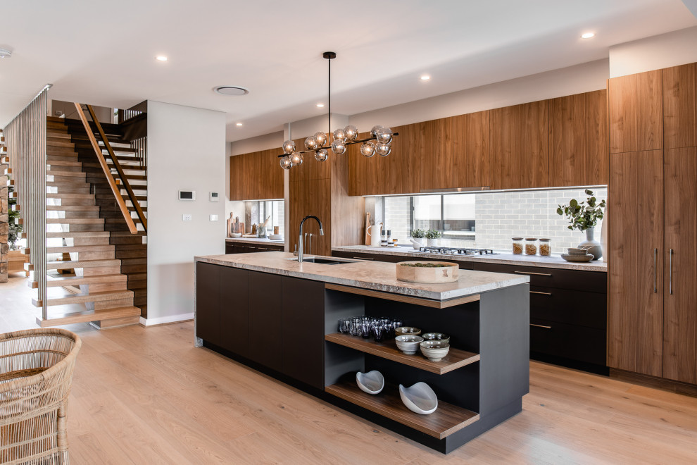 Photo of a contemporary galley kitchen in Sydney with an undermount sink, flat-panel cabinets, medium wood cabinets, window splashback, panelled appliances, light hardwood floors, with island, beige floor and grey benchtop.