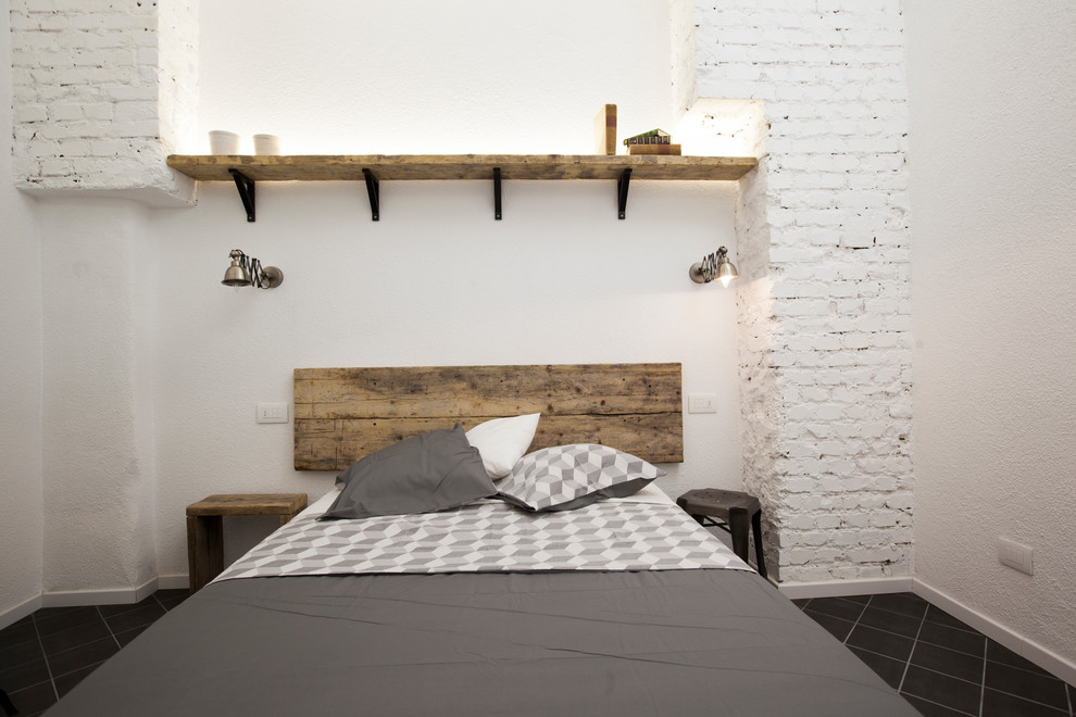 Photo of a mid-sized industrial master bedroom in Milan with white walls, porcelain floors and black floor.