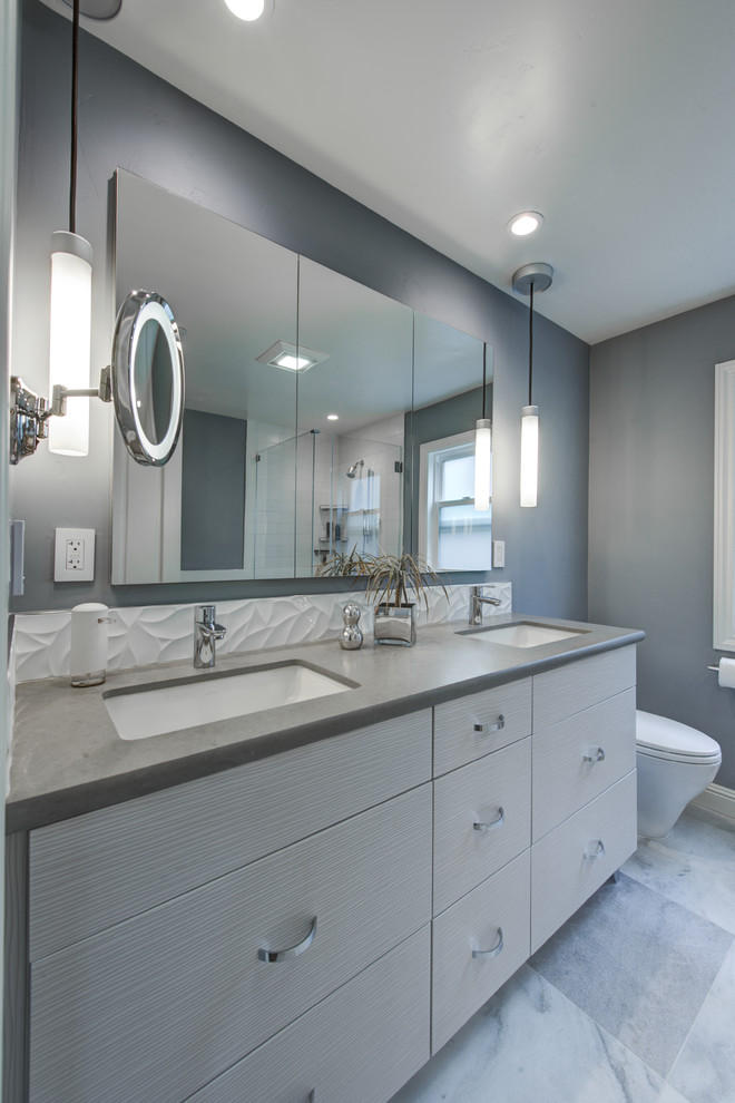 Photo of a mid-sized contemporary master bathroom in San Francisco with an undermount sink, flat-panel cabinets, white cabinets, engineered quartz benchtops, a corner shower, a one-piece toilet, white tile, porcelain tile, grey walls and marble floors.