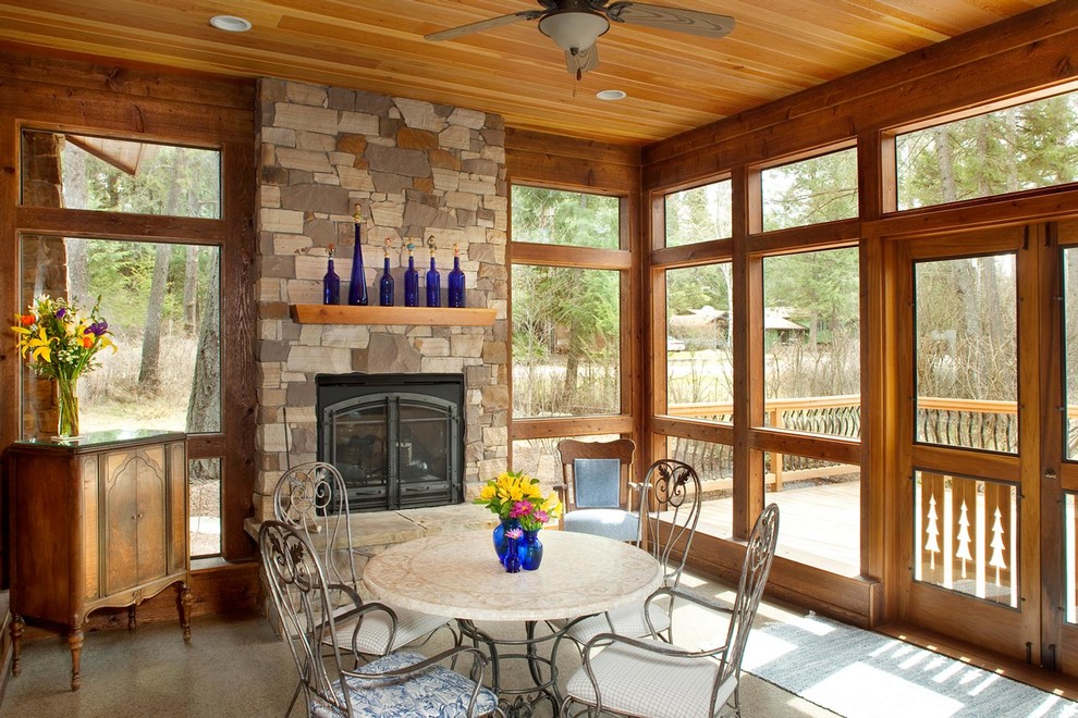 Country sunroom in Other with a standard ceiling, a stone fireplace surround and concrete floors.