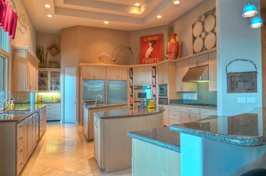 This is an example of an expansive contemporary u-shaped eat-in kitchen in Phoenix with a drop-in sink, open cabinets, beige cabinets, granite benchtops, grey splashback, stone slab splashback, stainless steel appliances, travertine floors and multiple islands.