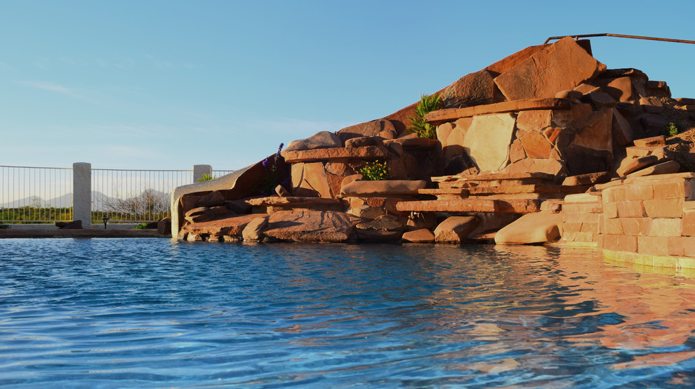 Hot tub - large backyard concrete paver and custom-shaped hot tub idea in Phoenix