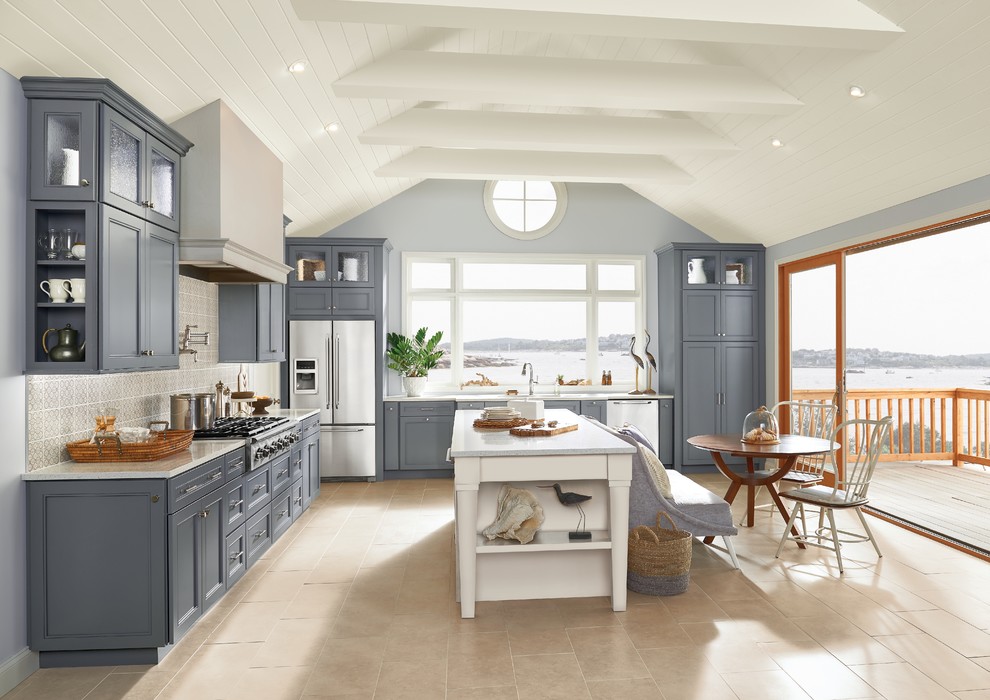This is an example of a large beach style l-shaped eat-in kitchen in New York with an undermount sink, white splashback, ceramic splashback, stainless steel appliances, with island, beige floor, white benchtop, recessed-panel cabinets, grey cabinets, quartz benchtops and porcelain floors.