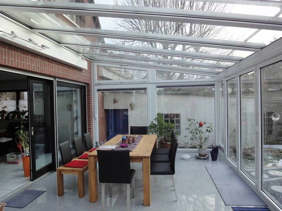 Photo of a large contemporary sunroom in Frankfurt with limestone floors, no fireplace, a glass ceiling and grey floor.