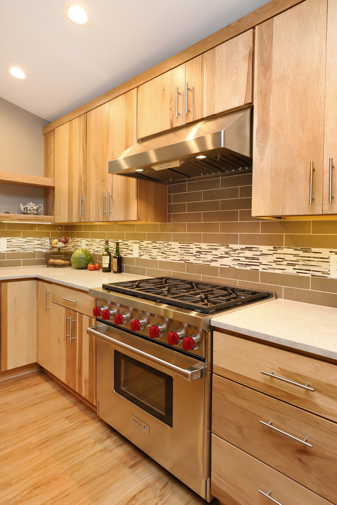 Example of a mid-sized transitional u-shaped light wood floor and brown floor eat-in kitchen design in Grand Rapids with an undermount sink, flat-panel cabinets, light wood cabinets, quartz countertops, brown backsplash, ceramic backsplash, stainless steel appliances and an island