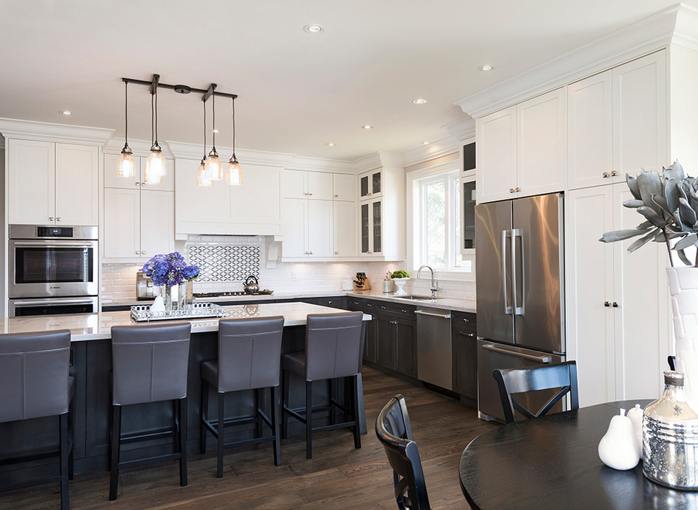 Large transitional l-shaped dark wood floor open concept kitchen photo in Toronto with an undermount sink, recessed-panel cabinets, white cabinets, quartzite countertops, white backsplash, subway tile backsplash, stainless steel appliances and an island