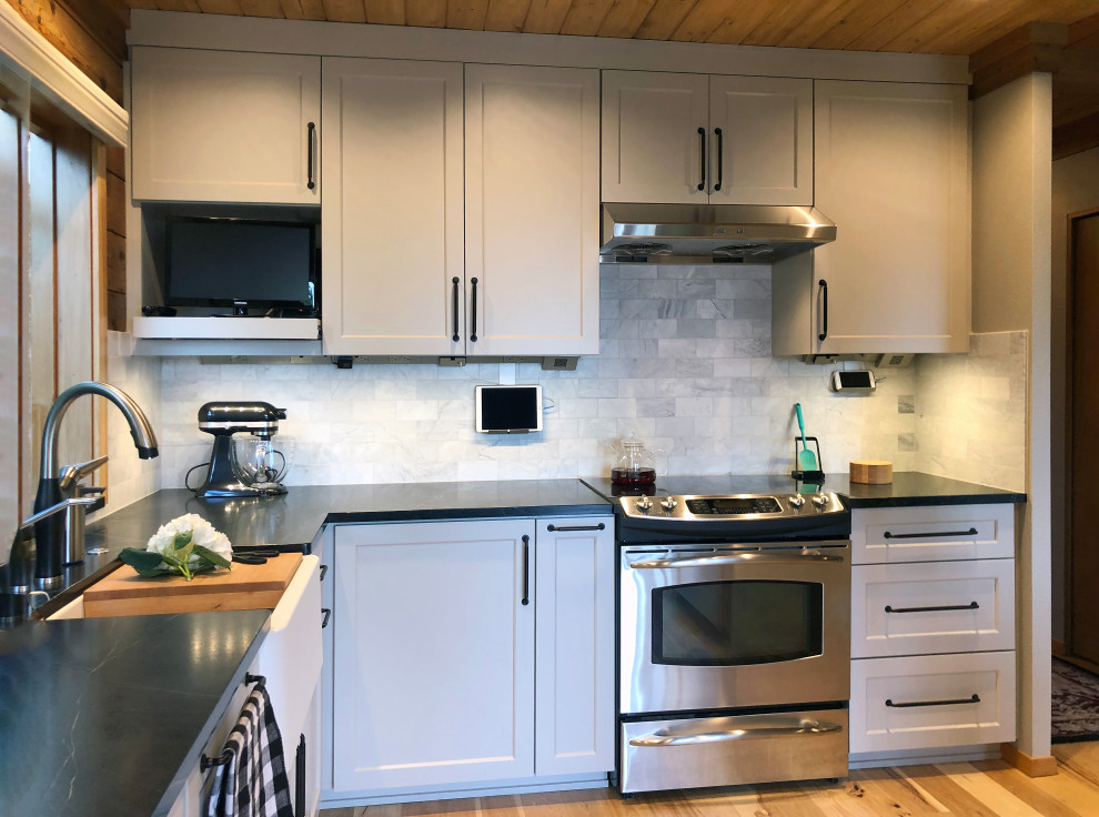 Idéer för att renovera ett mellanstort lantligt svart svart kök, med en rustik diskho, skåp i shakerstil, grå skåp, bänkskiva i täljsten, vitt stänkskydd, stänkskydd i marmor, rostfria vitvaror, ljust trägolv och gult golv